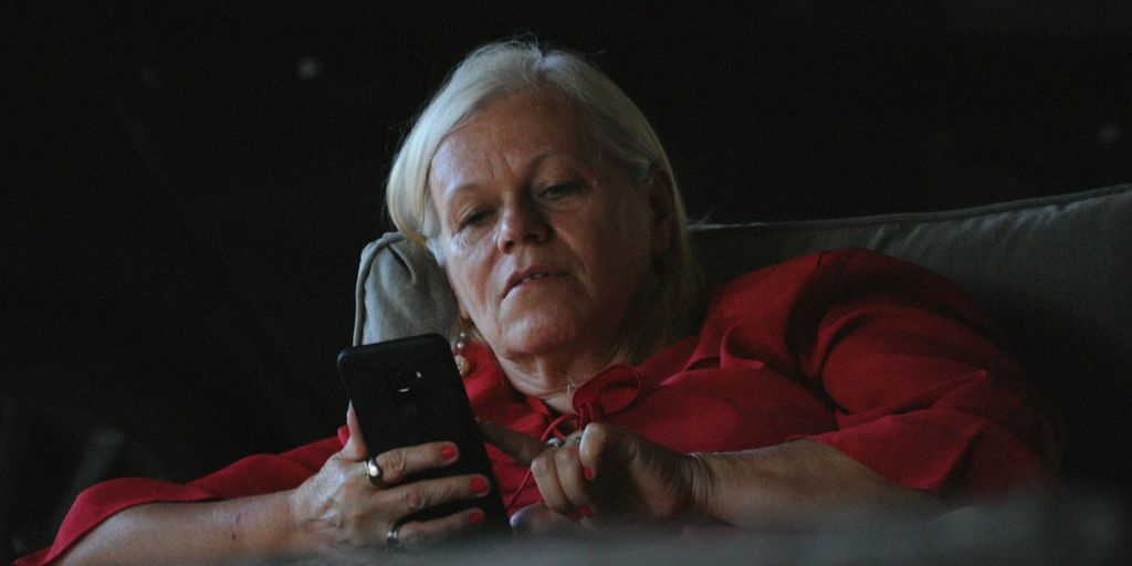 woman in red long sleeve shirt holding black smartphone