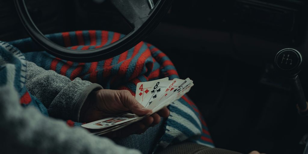 a person sitting in a car holding playing cards