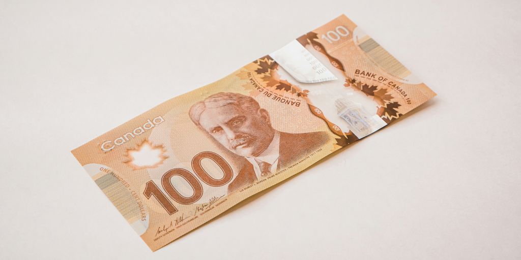 a canadian 100 dollar bill with a knife sticking out of it